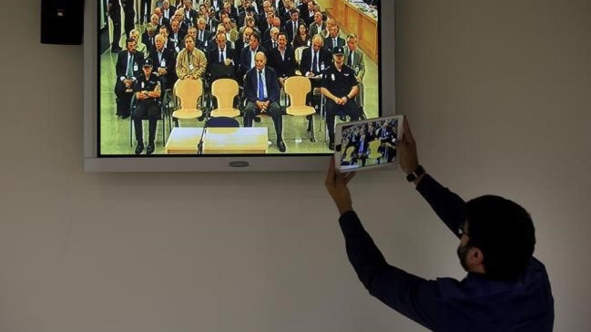 Un periodista hace una foto con una tablet a la pantalla de la sala de prensa, durante el juicio de las tarjetas black de Bankia  en la Audiencia Nacional