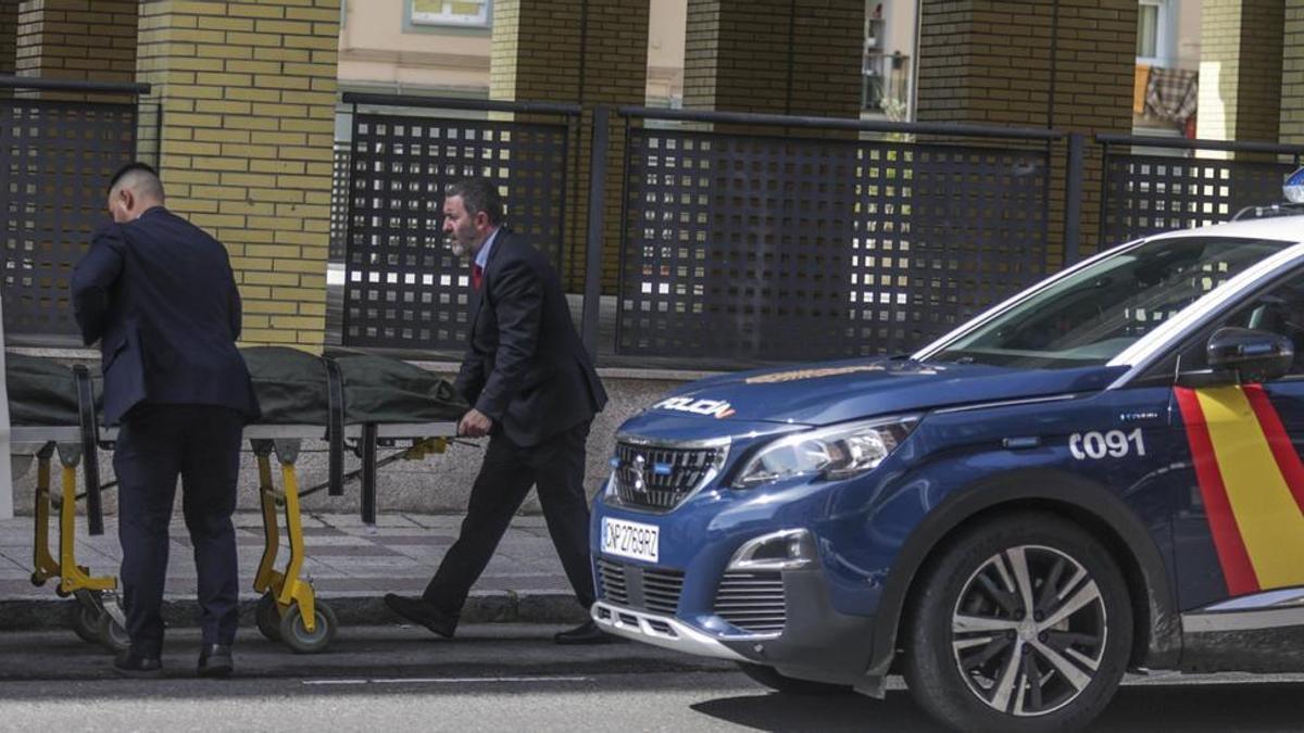 Empleados de la funeraria, introduciendo el cadáver en una furgoneta, ayer, en un bloque de pisos de la calle Ámsterdam