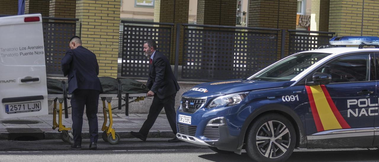 Empleados de la funeraria, introduciendo el cadáver en una furgoneta, ayer, en un bloque de pisos de la calle Ámsterdam