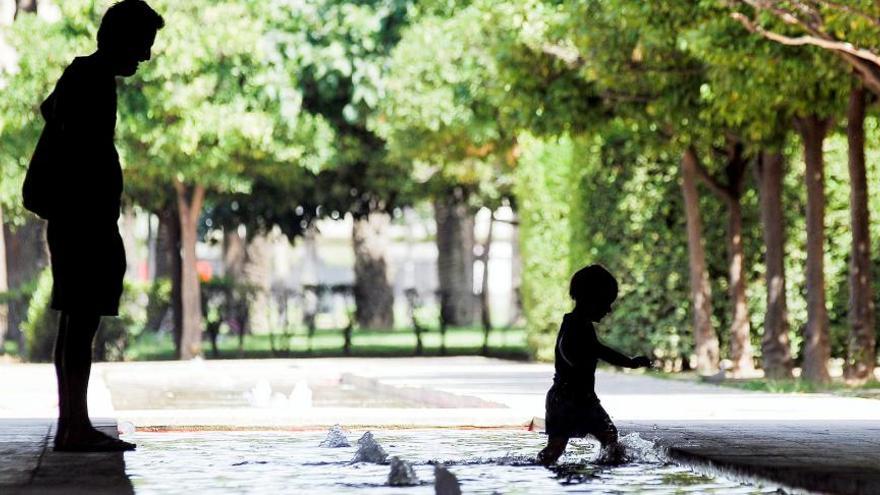 Un hombre y su hijo se refrescan en una fuente del Jardín del Turia.