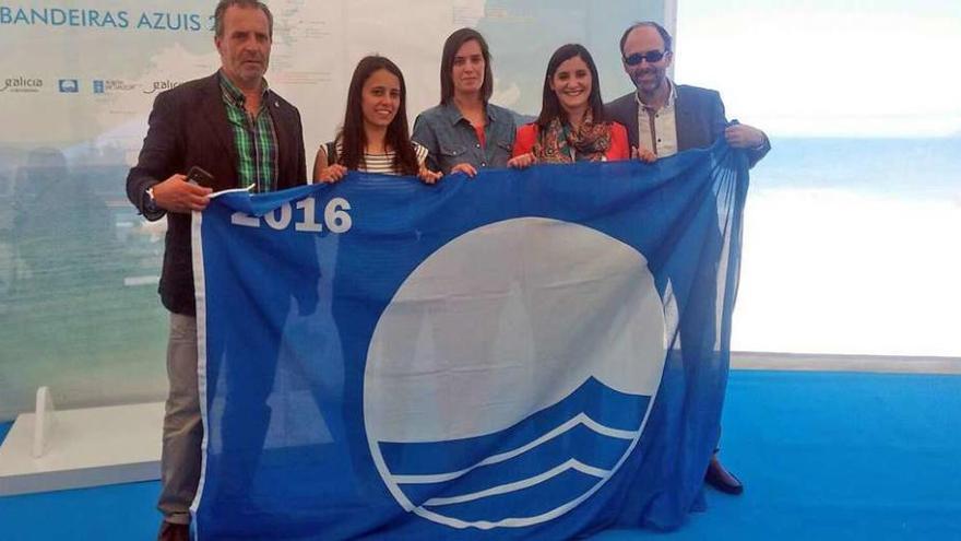 Representantes de los concellos de Bueu, Cangas y Moaña posando, ayer, con una de las banderas azules recibidas. // FdV