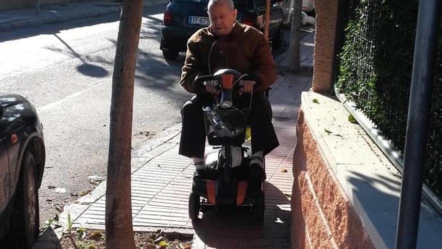 Una hombre trata de pasar con su andador junto a un alcorque.