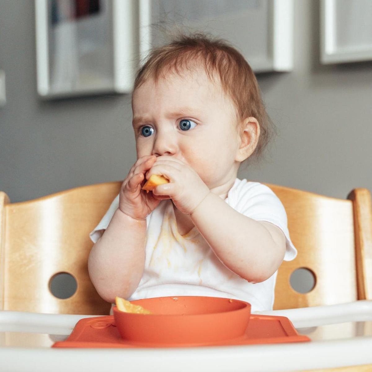 Un bebé comiendo fruta.