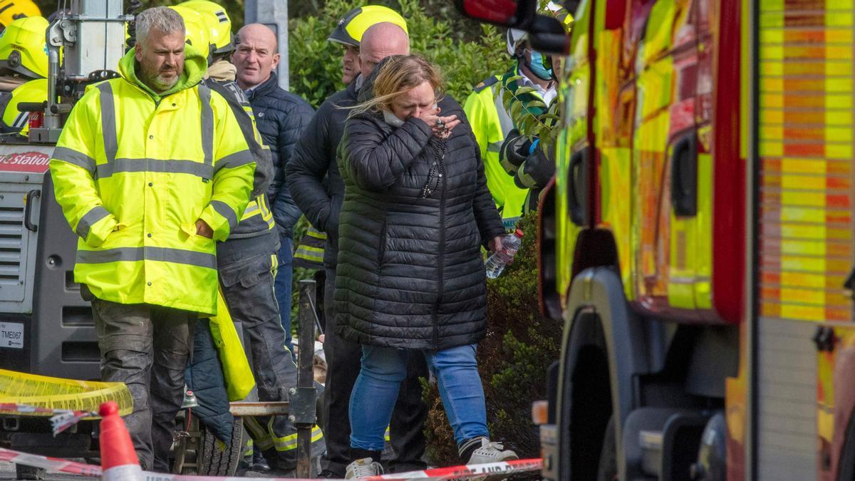 Una mujer  sostiene un rosario dentro del cordón de los servicios de emergencia en la escena de una explosión en Creeslough, en el noroeste de Irlanda, el 8 de octubre de 2022.