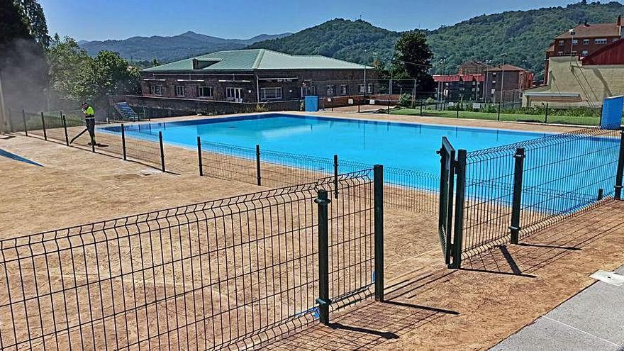 Un operario acondiciona el recinto de las piscinas de Riaño.