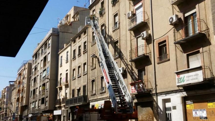 Los bomberos saneando la fachada con la ayuda de una larga escalera