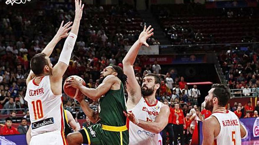 Víctor Claver y Marc Gasol intentan impedir la entrada a canasta del australiano Patty Mills, mientras Rudy Fernández aguarda el desenlace de la jugada.