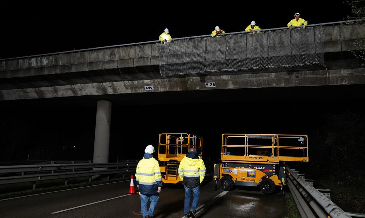Operarios, colocando la malla en el puente.
