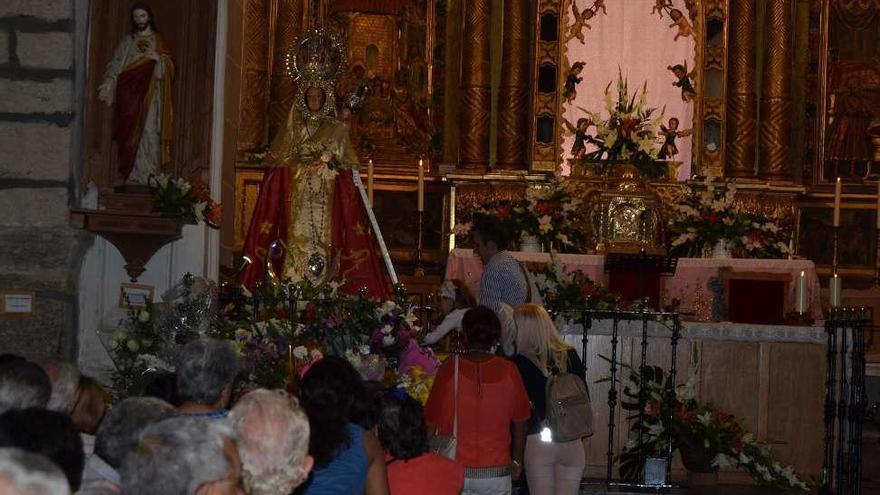 Un padre y su hija colocan el último ramo a los pies de la Virgen de la Carballeda.