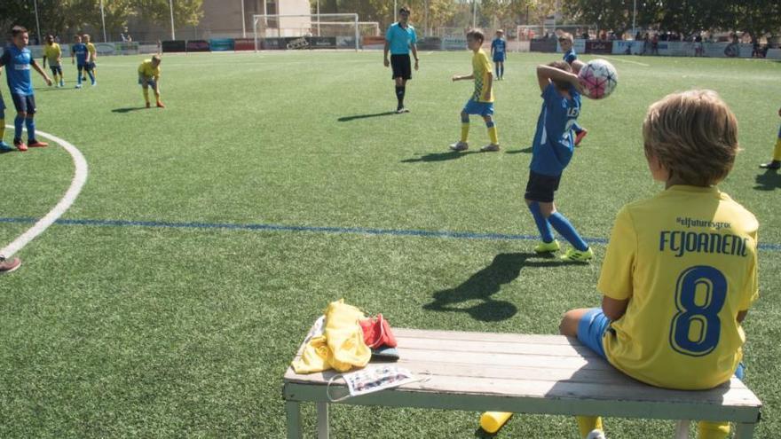 Partit de futbol base al camp del Joanenc, amb la mascareta a la banqueta |