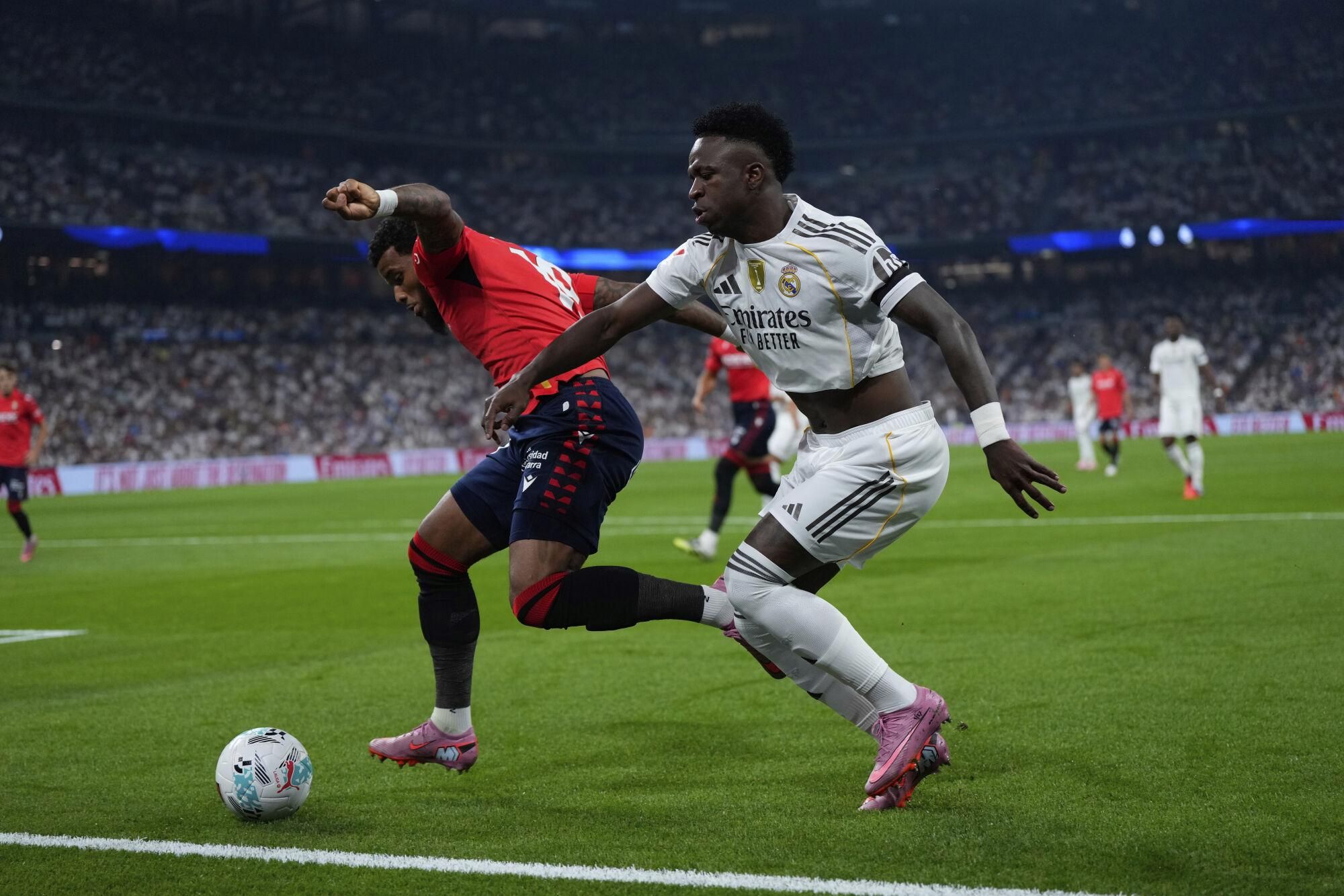 Osasuna's Valentin Rosier, left, and Real Madrid's Vinicius Junior fight for the ball during the La Liga soccer match between Real Madrid and Osasuna in Madrid, Spain, Tuesday, Aug. 19, 2025. (AP Photo/Manu Fernandez)