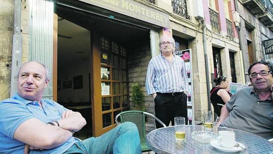 Antonio Fernández, propietario del bar Monterrey, en el centro, sirve a José Luis González y Fernado Larfeuil en la terraza del establecimiento.