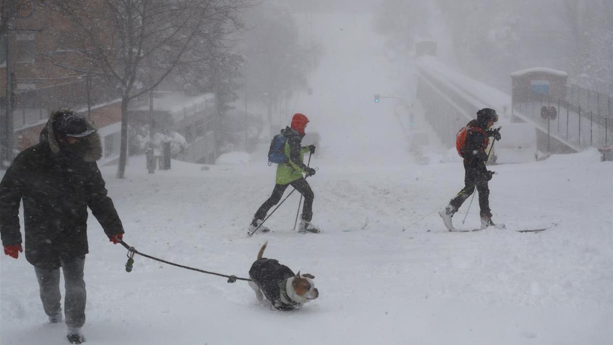 Viandantes en una calle cubierta de nieve en Madrid  este sabado  La Comunidad de Madrid ha despertado este sabado cubierta con una espesa manta de nieve que impide la movilidad en buena parte de la región  incluida la capital  donde el aeropuerto de Barajas ha tenido que suspender la actividad para todo el dia  los autobuses de la EMT no pueden circular  hay cortes puntuales en Metro y los vehiculos solo pueden moverse con cadenas  EFE  Ballesteros