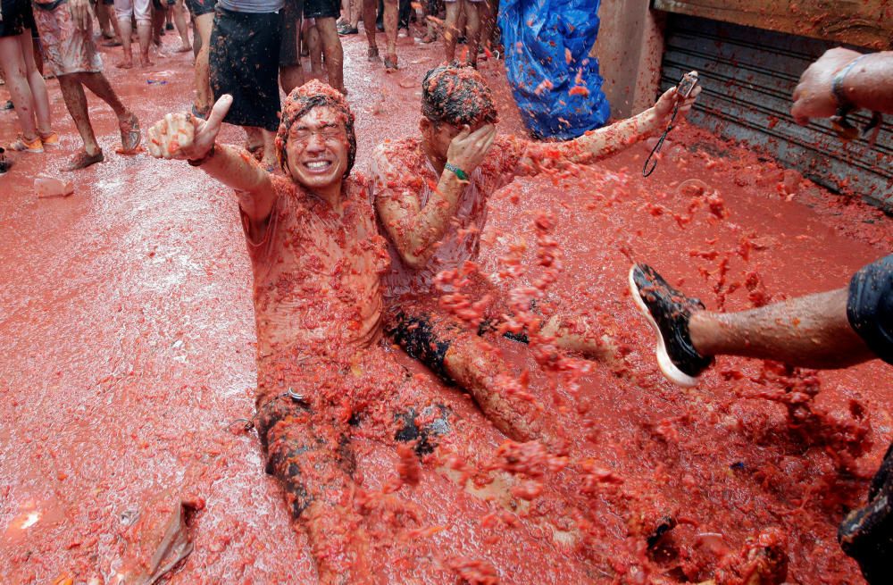 Revellers play with tomato pulp during the ...