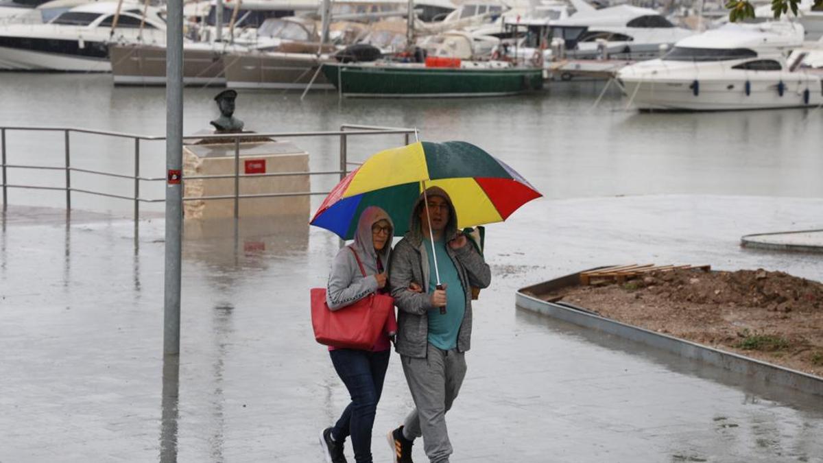 Dos personas pasean por el puerto de Alicante pese a la lluvia, este martes.