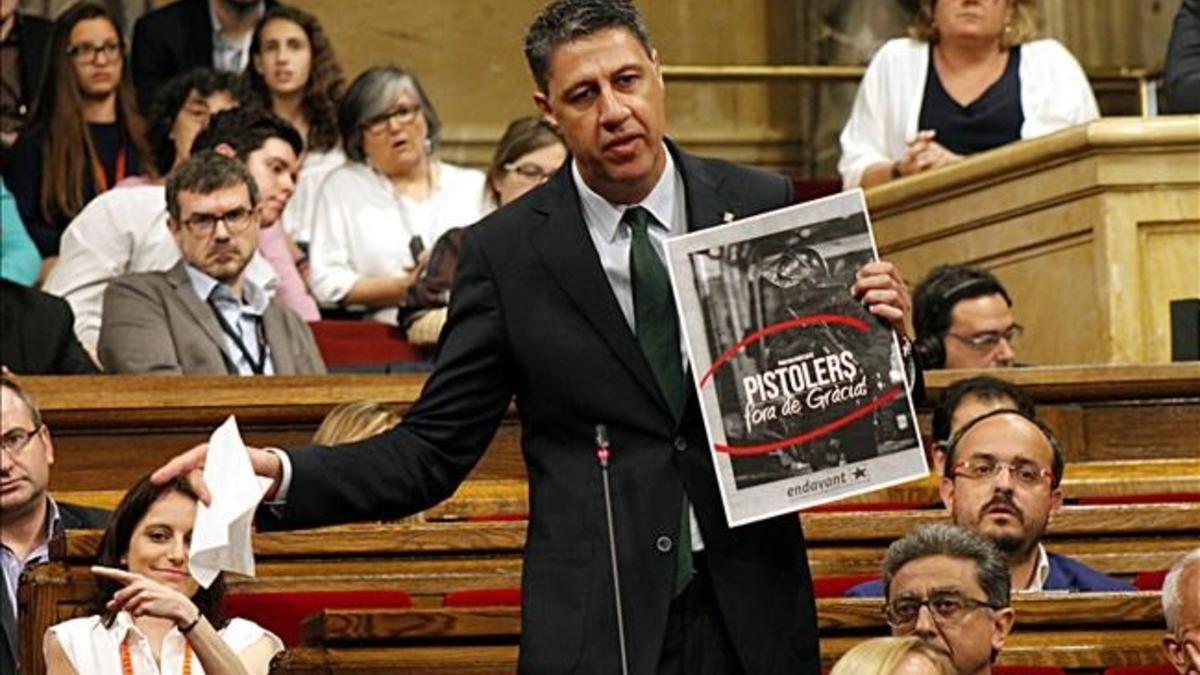 El presidente del grupo parlamentario del PPC, Xavier García Albiol, mostrando el cartel en el que responsabiliza a la CUP de los disturbios en Gràcia.