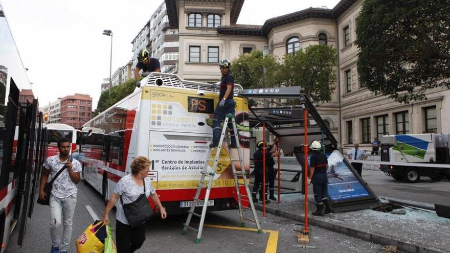 Bomberos retiran restos de la marquesina y desenganchan parte de la estructura del autobús. juan plaza