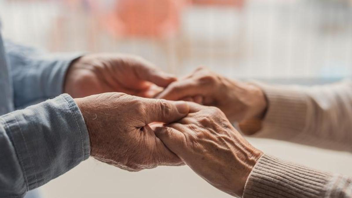 Dos personas hablan con las manos cogidas