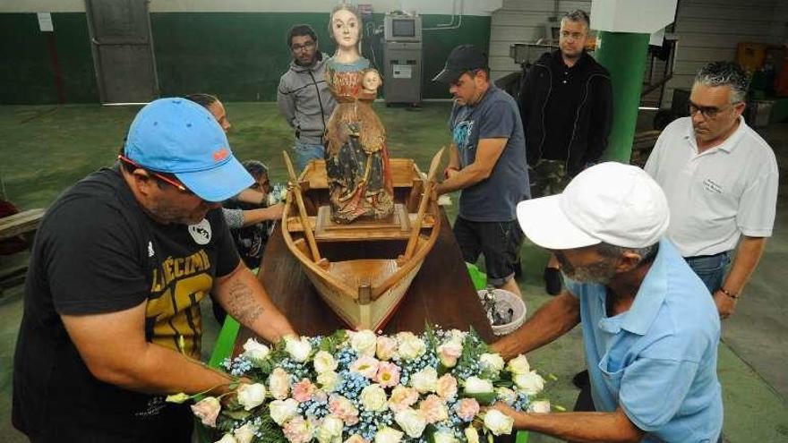 Los vecinos engalanan a la Virgen en la lonja de Carril. // Iñaki Abella