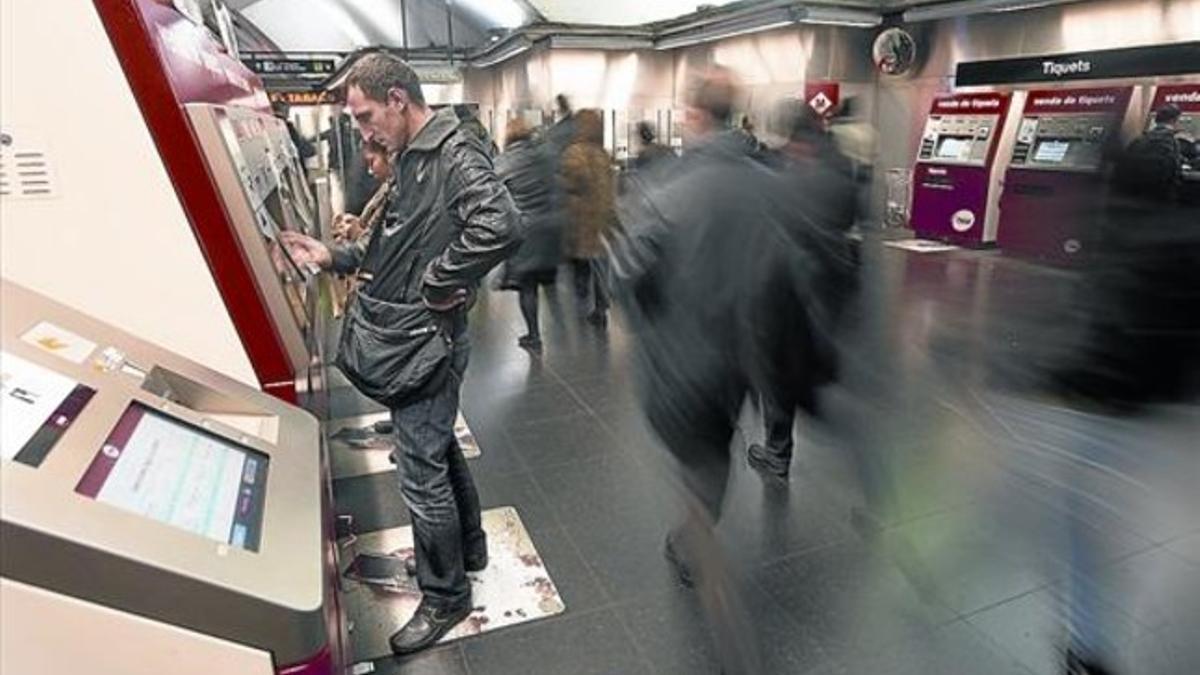 Unos usuarios adquieren billetes en las máquinas expendedoras de la estación del metro de Plaça d'Espanya.