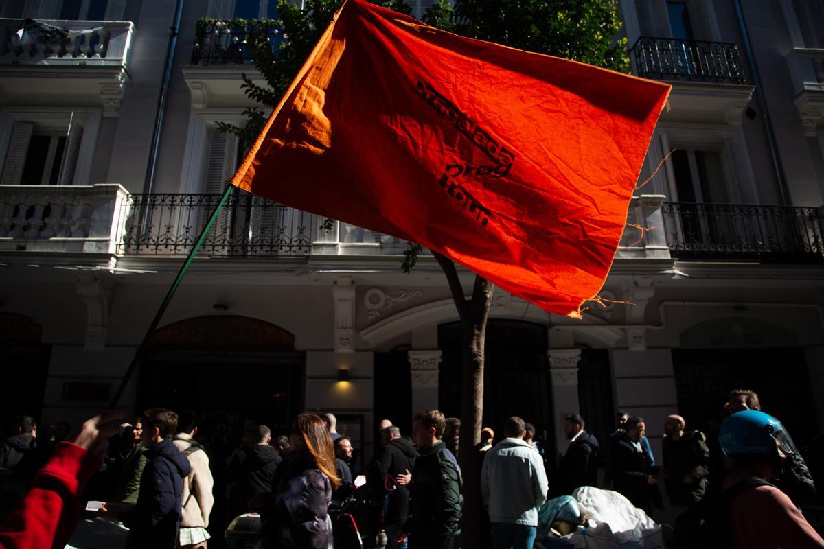 Uno de los guías de la Dragalada Drag Tour ondea una bandera a la salida de una de las salas que forman de Chueca en las que se celebra el evento, en Madrid.