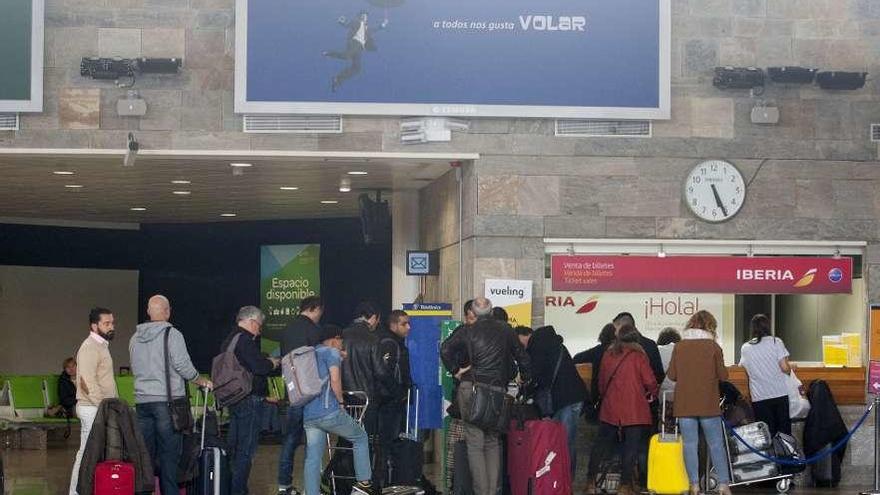 Viajeros en la terminal de Alvedro delante de un mostrador.