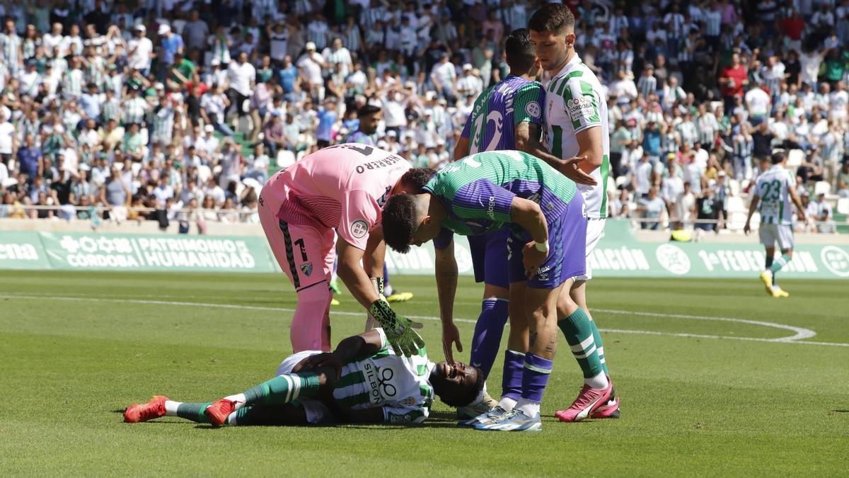 Jugadores del Málaga atienden a Adilson, que se duele en el suelo.