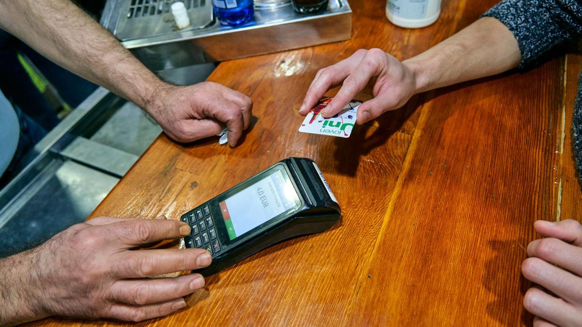 Una persona paga con una tarjeta en un bar.