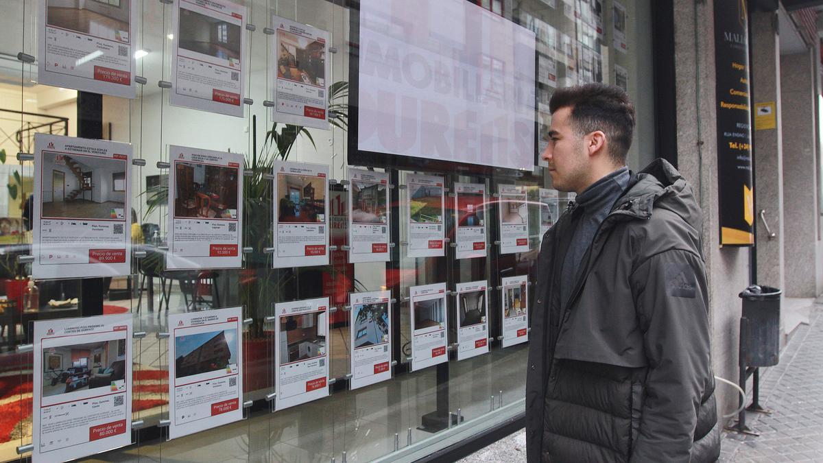 Un joven mira los anuncios de viviendas en una inmobiliaria.