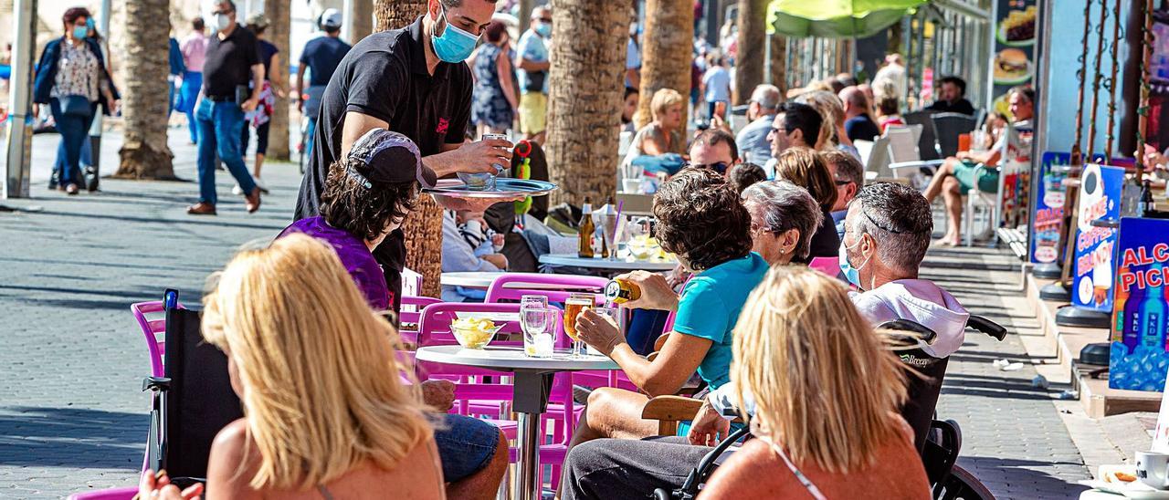 Imagen reciente de un camarero con mascarilla atendiendo la terraza de una cafetería de Benidorm.