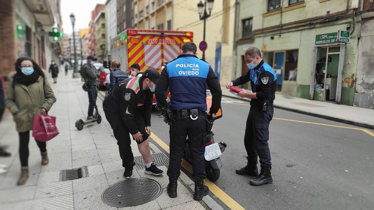 El trabajador muestra sus heridas a dos policías con la uvi móvil al fondo.