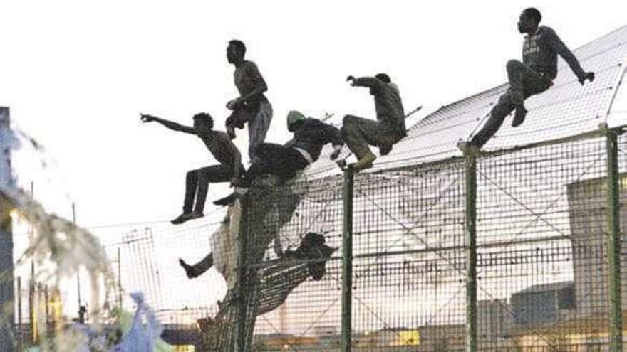 Migrantes subsaharianos, en un intento de salto a la valla. // Efe