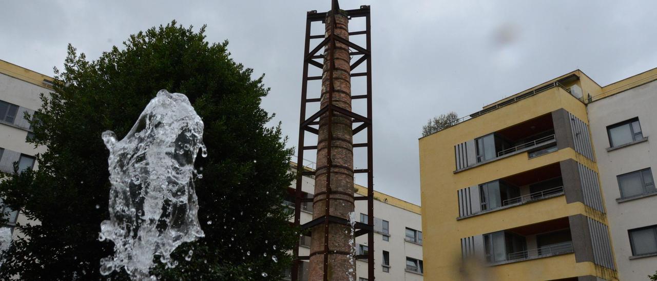 La chimenea de la antigua fábrica de Massó en Bueu, que el Concello se niega a recepcionar, al lado de la fuente cibernética.