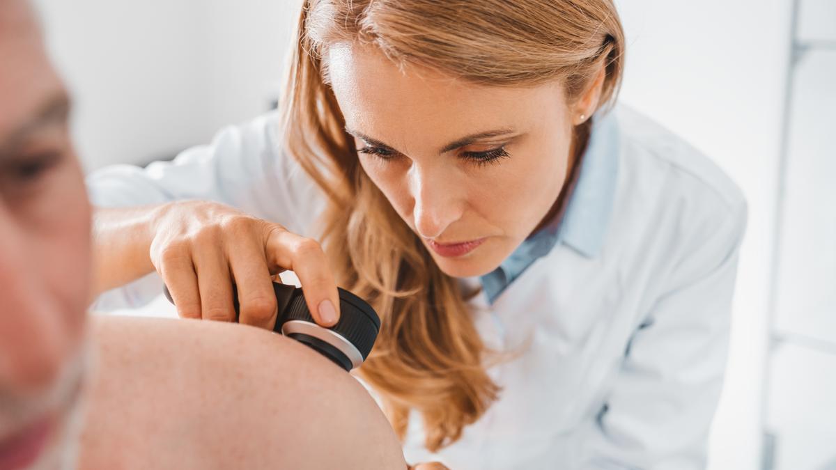 Una dermatóloga observa la piel de un paciente