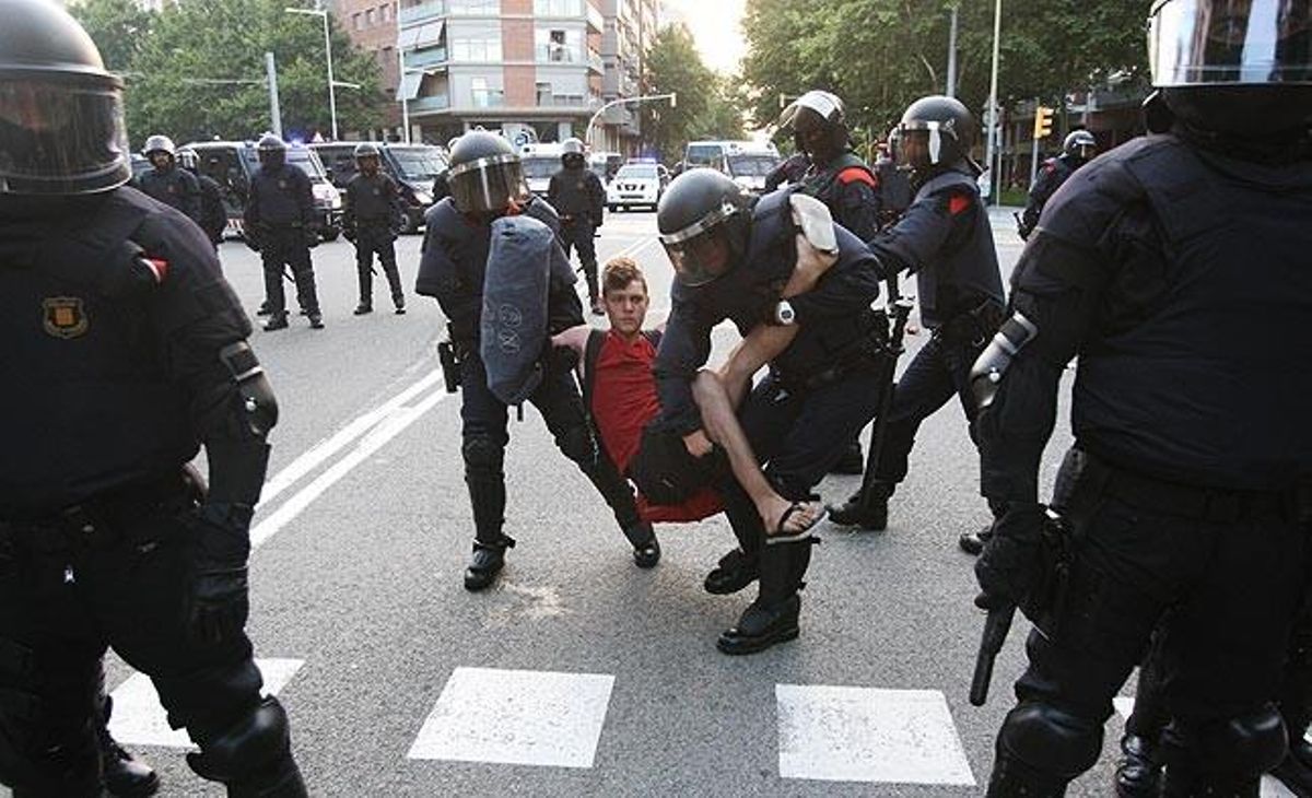 Diversos agents dels Mossos s’emporten un jove que moments abans estava assegut a terra.