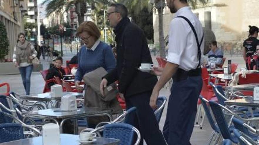 Un camarero sirviendo mesas en una plaza de Elche.