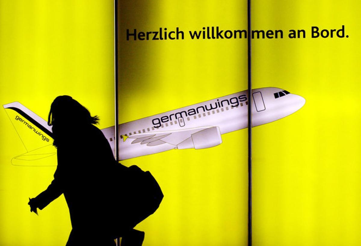 Una dona passa davant d’un cartell publicitari de Germanwings a l’aeroport de Colònia, a Alemanya.