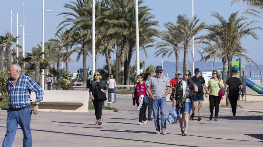 Personas paseando por primera línea de la playa de Gandia. | ÀLEX OLTRA