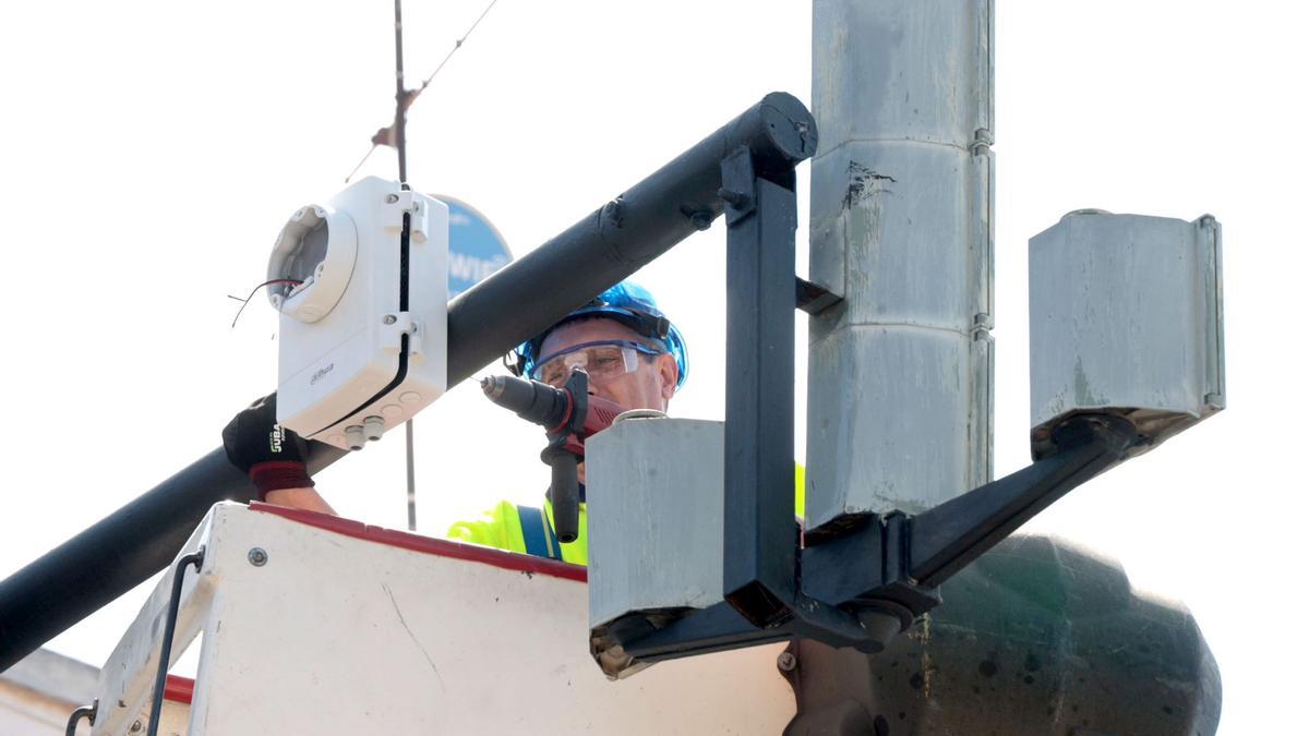 Un operario de la contrata municipal instala una cámara en un cruce semafórico del Camino Font d'En Cors, en la Punta