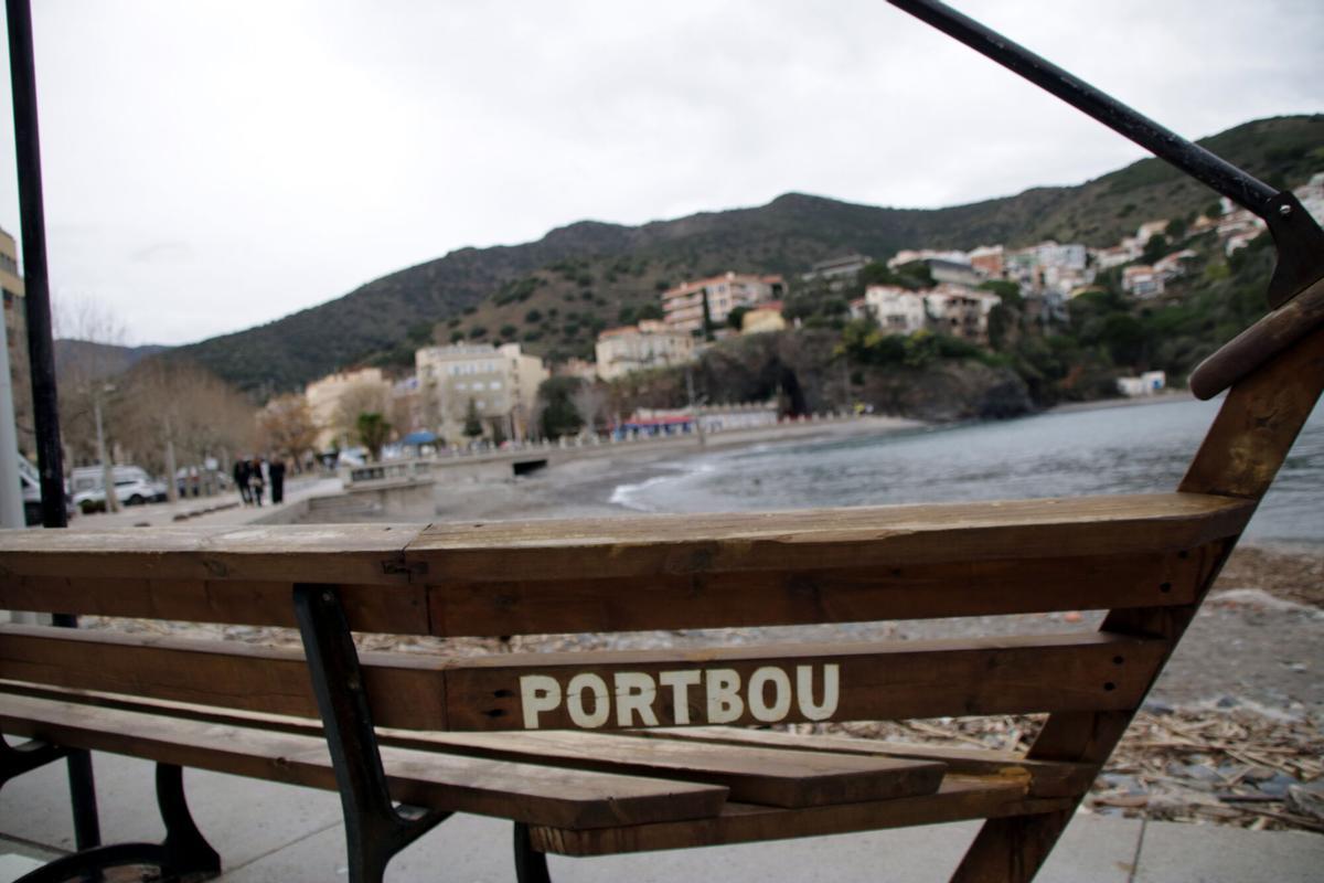 Un banc amb les lletres de 'Portbou'. De fons, el mar