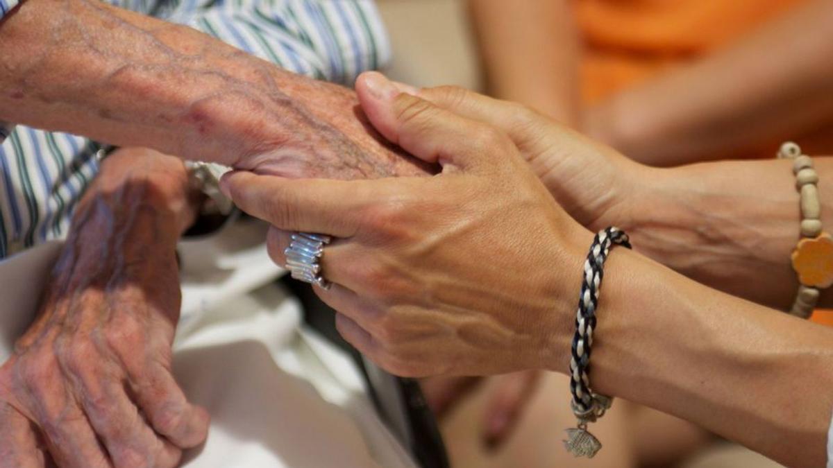 Una mujer sostiene la mano de una anciana.