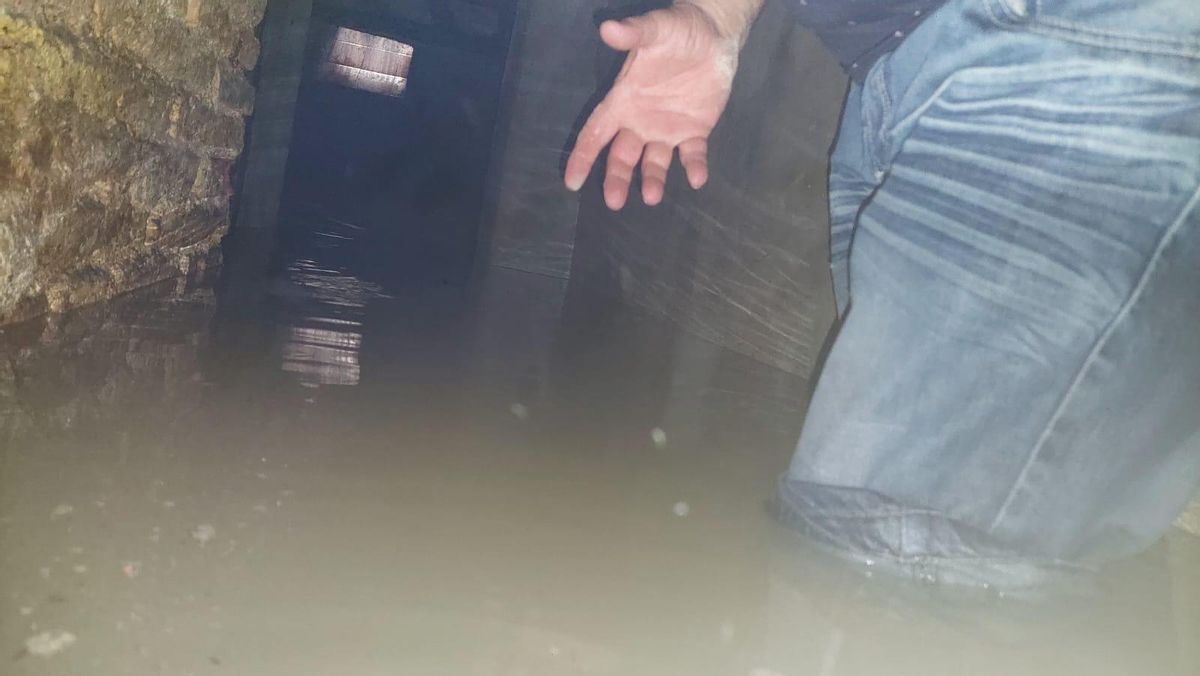 Carlos Martínez, un vecino de Zaragoza, en el sótano de la papelería Adjunto, con el agua por encima de la rodilla por el reventón de la tubería de la plaza San Miguel de Zaragoza, este jueves.