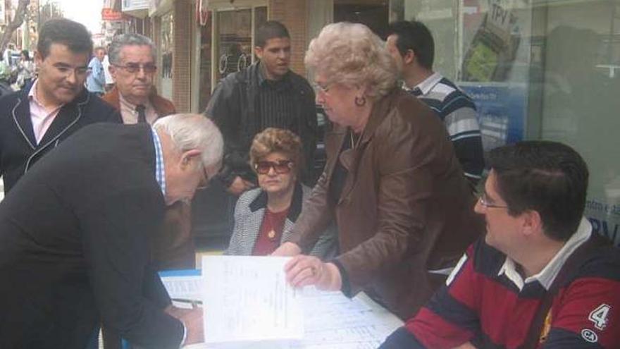 Un hombre firma en la mesa del PP, con Rubio a la derecha.