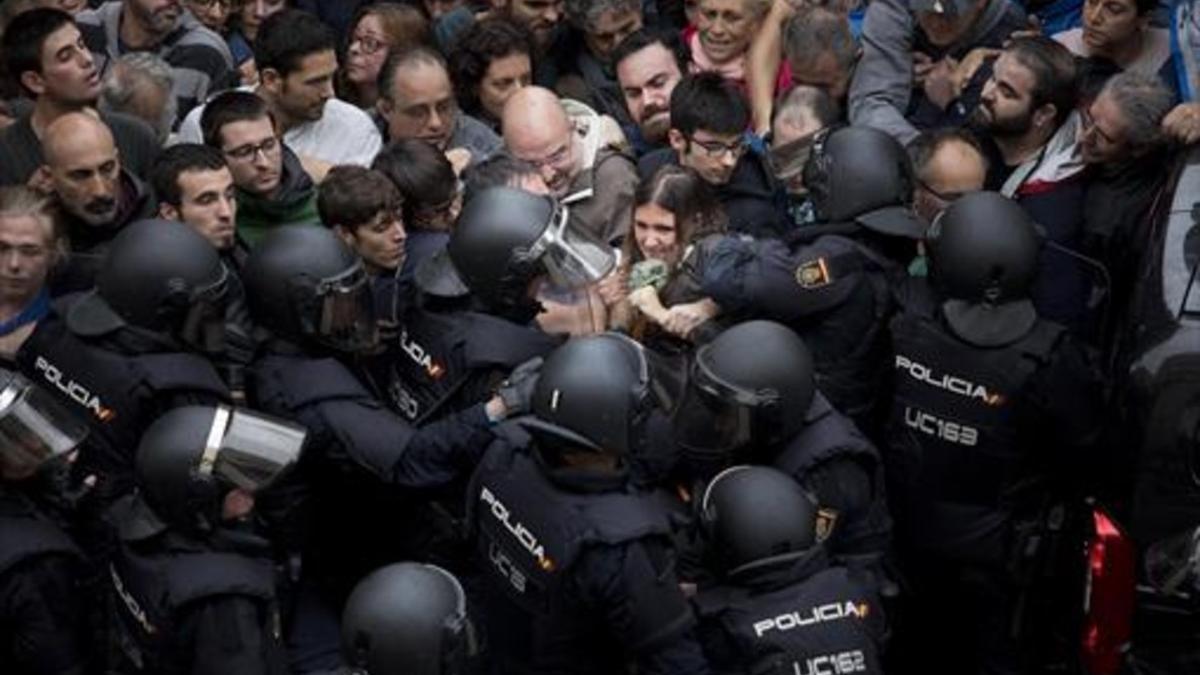 Agentes de la policía nacional intentan desalojar a las personas concentradas en las puertas del colegio Ramon Llull de Barcelona el 1-O.