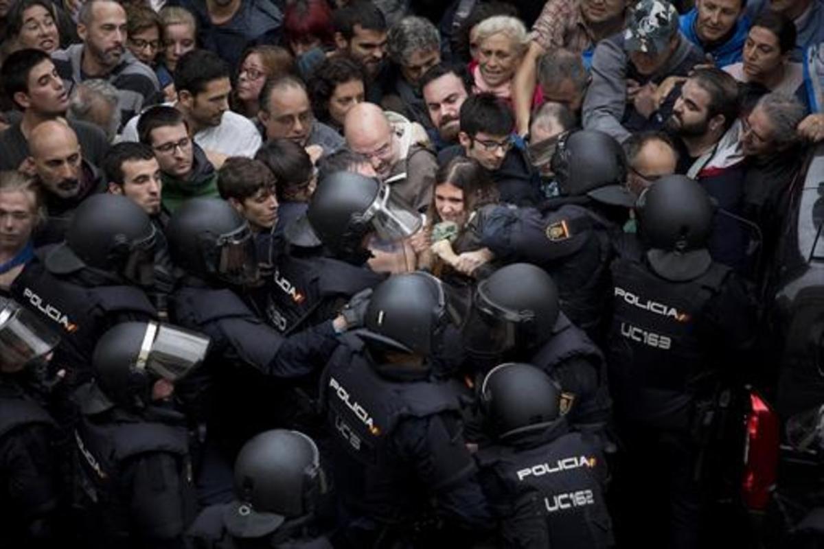 Agents de la policia nacional intenten desallotjar a les persones concentrades a les portes del col·legi Ramon Llull de Barcelona, l’1-O.