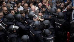 Agents de la policia nacional intenten desallotjar a les persones concentrades a les portes del col·legi Ramon Llull de Barcelona, l’1-O.