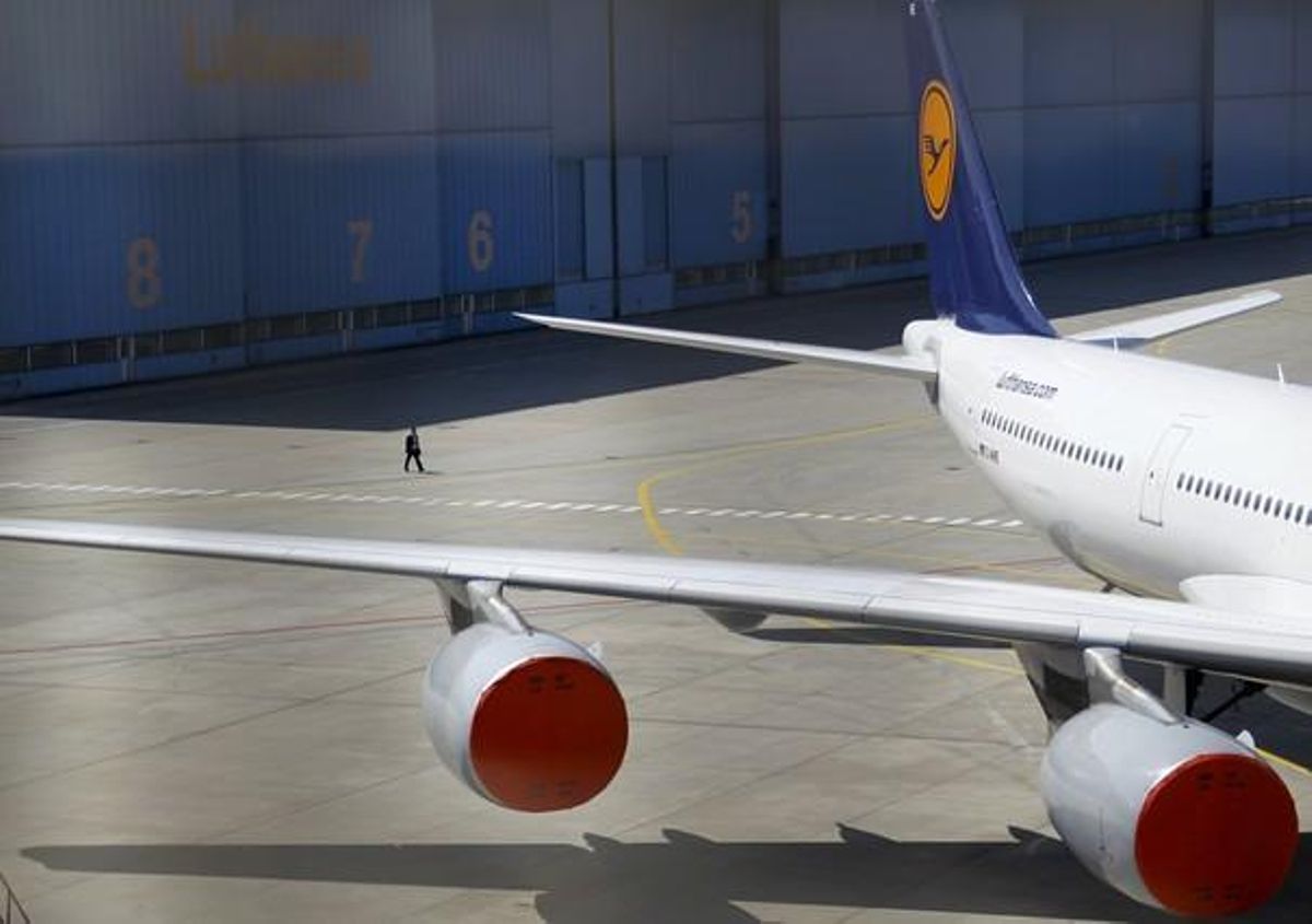 A man passes covered turbines of a parked Lufthansa plane at the closed Frankfurt Airport