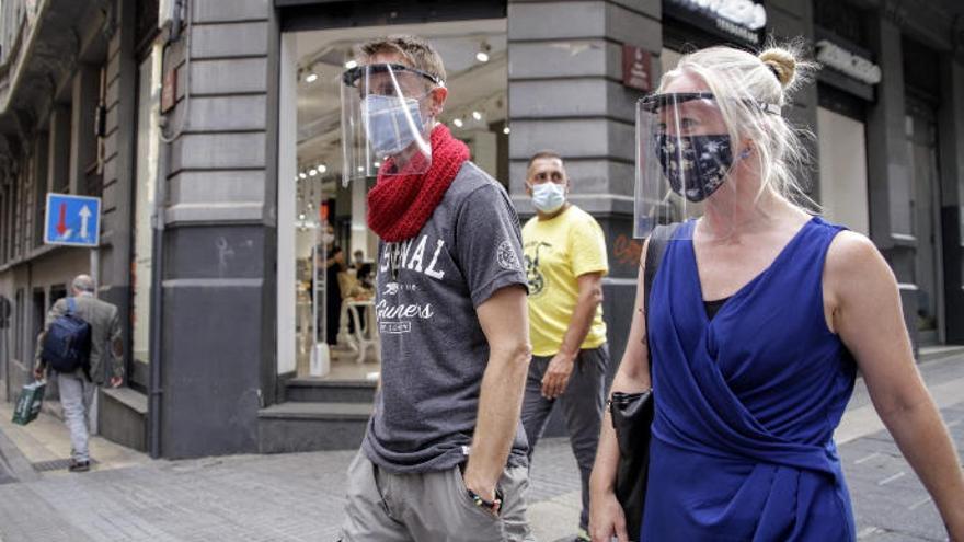 Una pareja camina ayer por la calle Castillo con una visera protectora.