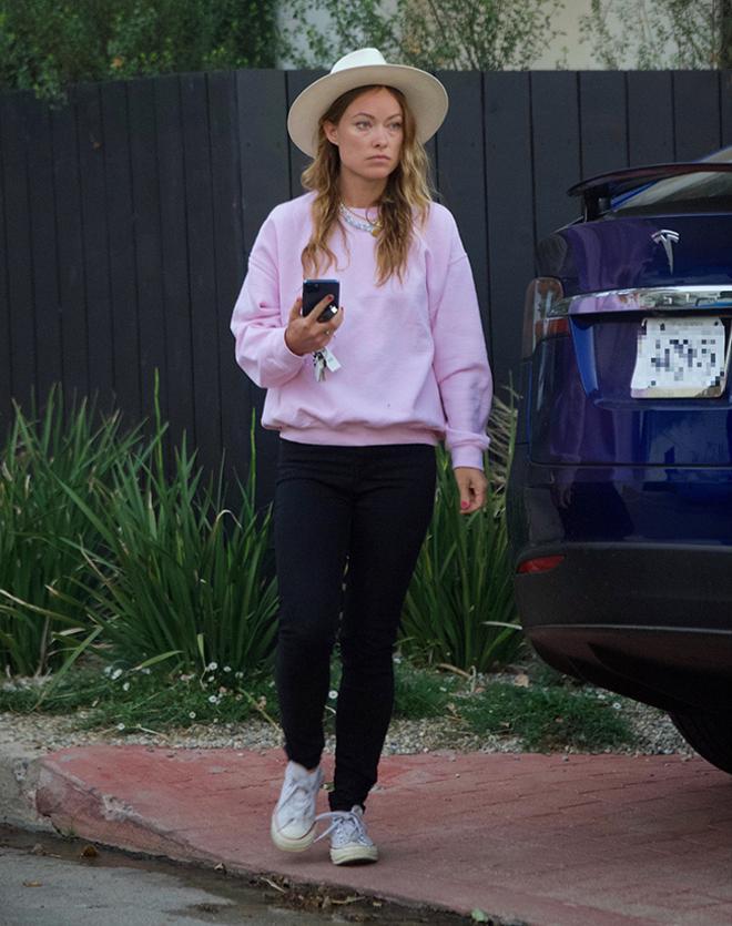 Olivia Wilde con jeans pitillo negros y sudadera rosa