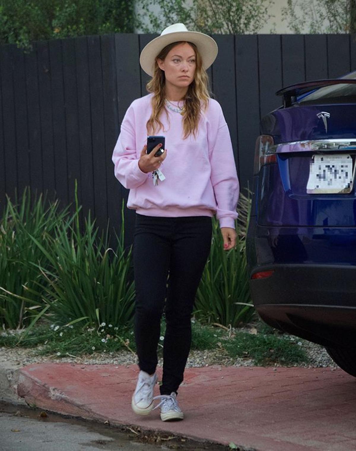 Olivia Wilde con jeans pitillo negros y sudadera rosa